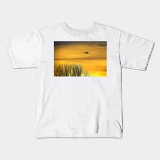 Swan flying into a golden dawn Kids T-Shirt